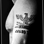 Фото тату на плече с изображением римского орла, штандарта и надписи 'LEGIO X'. Татуировка выполнена в графическом стиле черными чернилами.