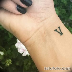 Фото тату на запястье с изображением римской цифры 'V', выполненное в минималистичном стиле черными чернилами. Небольшая и стильная татуировка.