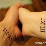 Фото тату на запястьях двух людей с изображением римских цифр, выполненное в минималистичном стиле черными чернилами. Символ любви и единства.