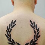 Фото тату: черный лавровый венок, расположенный на спине. Символ победы и славы, выполненный в графическом стиле.