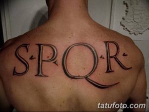 Фото тату с надписью SPQR на спине мужчины. Черные буквы классического шрифта, символизирующие римскую республику.