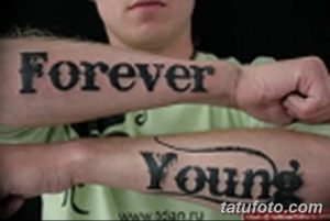 Фото тату с надписью 'Forever' на одном предплечье и 'Young' на другом. Рисунок выполнен в черных тонах.
