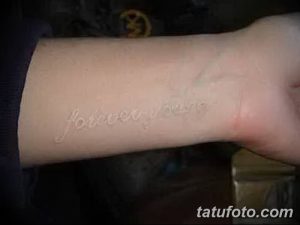 Фото тату с белой надписью 'Forever Young' на запястье. Татуировка выполнена в минималистичном стиле.