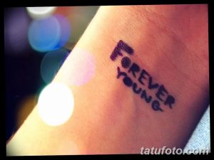 Фотография татуировки с надписью 'Forever Young', выполненной в блочном стиле на запястье. Современный и стильный рисунок татуировки.