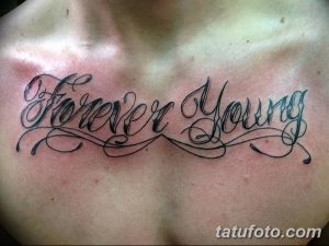 Фотография татуировки с надписью 'Forever Young', выполненной каллиграфическим шрифтом на груди. Красивый и выразительный рисунок татуировки.
