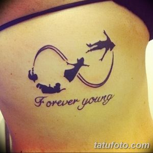 Фото татуировки с надписью 'Forever Young' и силуэтами Питера Пэна и Венди, заключенными в символ бесконечности. Оригинальный рисунок татуировки на плече.