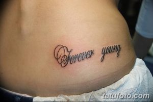 Фотография татуировки с надписью 'Forever Young', выполненной черным цветом на талии. Простой и элегантный рисунок татуировки для девушек.