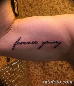 Фото тату надписи 'Forever Young' выполненной каллиграфическим шрифтом на руке. Минималистичная и элегантная татуировка.