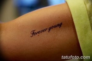 Фото тату надписи 'Forever Young' выполненной простым шрифтом на запястье. Небольшая и аккуратная татуировка.