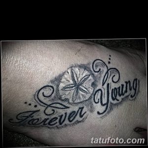 Фото татуировки надписи 'Forever Young' с изображением морской звезды на руке.