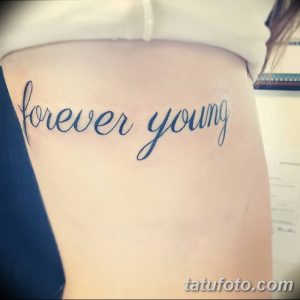 Фото татуировки надписи 'Forever Young' выполненной изящным шрифтом на женской спине.