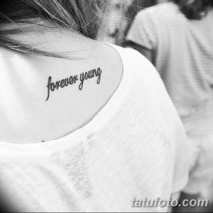 Фото тату с надписью 'Forever Young' на шее девушки. Нежная и изящная татуировка, выполненная тонким шрифтом в черном цвете.