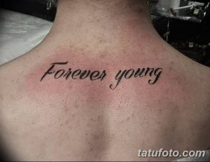 Фото тату с надписью 'Forever Young' на груди мужчины. Классическая татуировка, выполненная черным цветом, подчеркивающая мужественность.