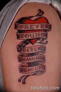 Фото тату в виде сердца с надписями 'Forever Young' и именами 'Derek', 'Hannah', 'Emily' на плече. Семейная татуировка, выполненная в черном цвете.