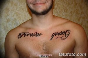 Фото тату с надписью 'Forever Young' на груди у мужчины, выполненной черным шрифтом. Классический дизайн на светлой коже.