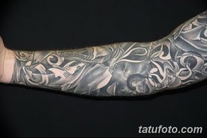 Фото тату в стиле рукав на руке, изображающего морскую тематику: акулы, осьминоги, волны и другие морские обитатели. Детализированный рисунок татуировки.