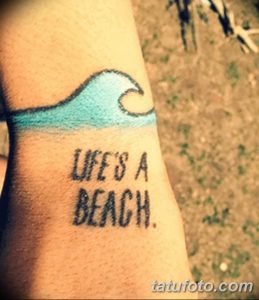 Фото тату волны и надписи 'Life's a Beach' на запястье. Минималистичный рисунок татуировки в черно-белых тонах.