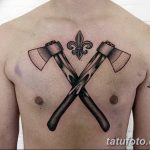 Фото татуировки с изображением двух скрещенных топоров и символа флер-де-лис на груди мужчины. Строгий и лаконичный черно-белый рисунок.