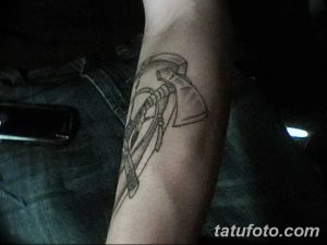 Фото эскиза татуировки томагавка с пером, предназначенного для нанесения на предплечье. Черно-белый рисунок с четкими контурами.
