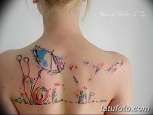 Фото тату: акварельная татуировка с изображением улитки, держащей воздушные шары. Нежные цвета, размытые контуры, мечтательный стиль.