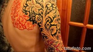 Фото тату: рукав, украшенный сложным цветочным орнаментом в восточном стиле. Яркие оранжевые и золотые цветы на черном фоне.