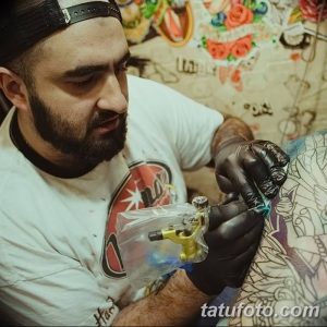 Фото татуировки, показывающее процесс нанесения татуировки на руку. Мастер сосредоточенно работает, используя тату-машинку.