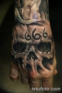 Фото тату: татуировка черепа с числом 666 на руке, реалистичный стиль, темные тона, зловещий дизайн.