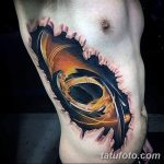 Фотография татуировки на боку, создающей 3D эффект разрыва кожи, из которого виднеется яркий абстрактный узор.