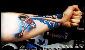 Фото тату на руке с изображением Луффи, главного героя аниме One Piece. Цветной рисунок в стиле аниме с яркими красками и динамичной позой.