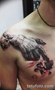 Фото татуировки руки, словно вырывающейся из пазла, на груди. Реалистичный рисунок с элементами сюрреализма и детализированными тенями.