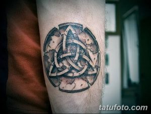 Фото тату кельтского узла в круге. Черно-серый рисунок с детализированной текстурой, имитирующей камень, и сложным переплетением линий.