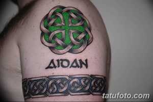 Фото татуировки кельтского узла с именем 'AIDAN' и кельтским браслетом на руке. Зеленый, синий и черный рисунок.