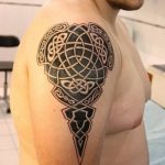 Фото тату кельтского узора на плече. Черно-серый рисунок с переплетающимися линиями и геометрическими формами, создающими сложный орнамент.