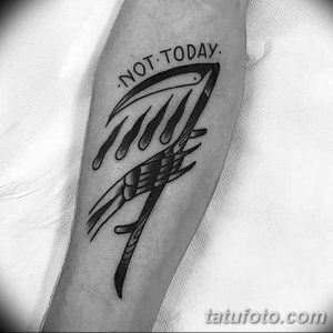 Черно-белая татуировка на предплечье с изображением косы и надписью 'Not Today'. Стиль old school, смелый дизайн, символическое значение.