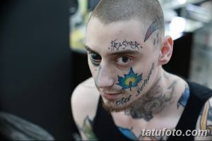 Фото тату: мужчина с множеством татуировок на лице, включая надписи и символы. Экстремальный стиль, яркие цвета, смелый дизайн.