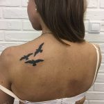 Фото тату трех летящих птиц на шее, выполненное в минималистичном стиле. Небольшой, но символичный рисунок татуировки.