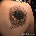 Крупный реалистичный рисунок подсолнуха с надписью 'Alexia' на плече, выполненный в черно-серых тонах.