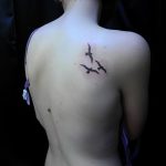 Фото небольшой татуировки с изображением трех птиц на лопатке. Черные силуэты птиц, символизирующие свободу, мечты и стремление к новым высотам.