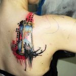 Фото тату песочных часов на спине. Изображение выполнено в сочетании черного, красного и голубого цветов с использованием акварельной техники, символизируя течение времени.