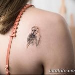 Фото минималистичной татуировки совы на плече. Черно-белый рисунок, выполненный тонкими линиями.