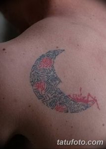 Фото тату в виде полумесяца, заполненного сложным орнаментом, на груди. Рисунок выполнен в черно-красных тонах, с использованием тонких линий и геометрических фигур.