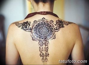 Фото татуировки в стиле мехенди на спине женщины. Сложный и детализированный рисунок татуировки в черном цвете.
