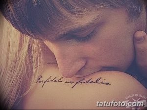 Фото тату латинской фразы на лопатке. Элегантная татуировка с надписью на латыни, выполненная изящным шрифтом.