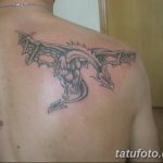 Фото тату дракона на спине. Детализированный рисунок мифического существа в черно-серых тонах, с расправленными крыльями и острыми когтями.