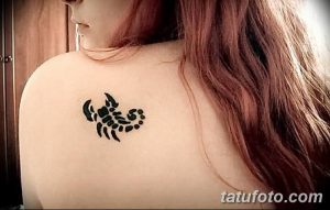 Фото тату: небольшой черный скорпион на лопатке. Простой и элегантный рисунок татуировки, выполненный в графическом стиле.