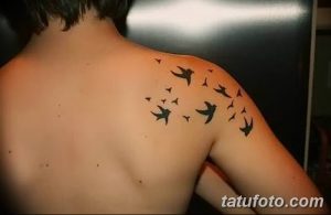 Фото тату: стая маленьких черных птиц, летящих в разные стороны, выполненная на плече. Простой и элегантный дизайн.