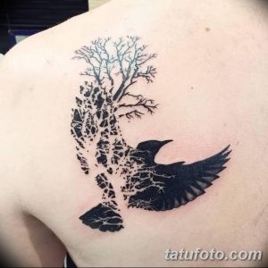 Фото тату дерева и ворона на плече, выполненное в стиле blackwork с использованием только черных линий и точек. Минималистичный и стильный рисунок.