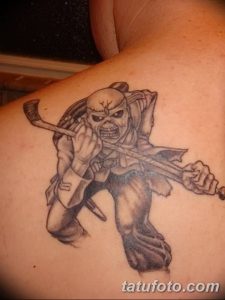 Фото тату на лопатке с изображением Эдди, талисмана группы Iron Maiden. Татуировка выполнена в черно-серых тонах с детальной проработкой.