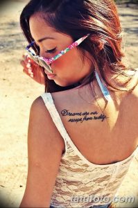 Фото тату надписи "Dreams are our escape from reality" на спине. Элегантный шрифт, вдохновляющий смысл. Подходит для мечтательных и творческих людей.