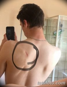 Фото тату: эскиз татуировки в виде незавершенного круга, нарисованный на спине мужчины. Черный контур и минималистичный дизайн.